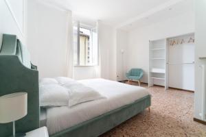 - une chambre blanche avec un lit et une chaise bleue dans l'établissement Spacious Apartment - 4 Bedrooms and 3 Bathrooms, à Bergame