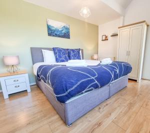 a bedroom with a bed with a blue comforter at Milton Keynes Modern City House in Milton Keynes
