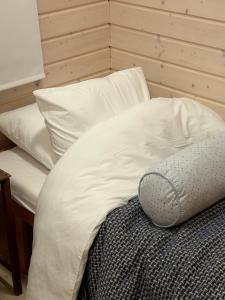 a bed with white sheets and a pillow on it at Sauna cabin in the heart of Nuuksio National Park in Espoo