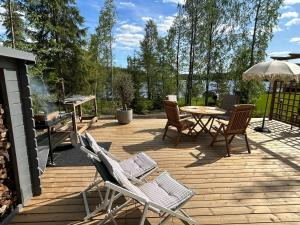 a deck with chairs and a table and an umbrella at Sauna cabin in the heart of Nuuksio National Park - Mökki Nuuksiossa in Espoo