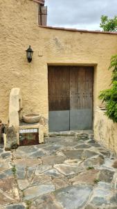 a garage with a wooden door and a bench in front at Casa Rural Lares in Casas de Don Pedro