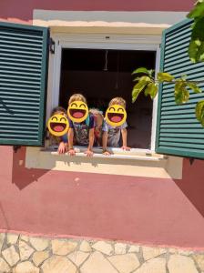 three children are looking out of a window at Melidron in Lixouri