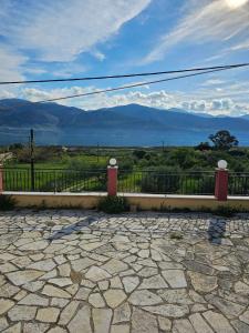 a stone patio with a fence and mountains in the background at Melidron in Lixouri
