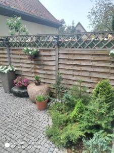 a wooden fence with potted plants in a garden at Konik Bar i Pokoje Gościnne in Kadyny