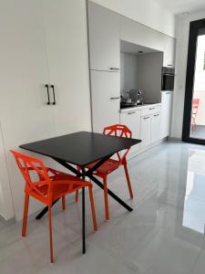 Una cocina con una mesa negra y dos sillas naranjas. en Luxury Living Martigues, en Martigues