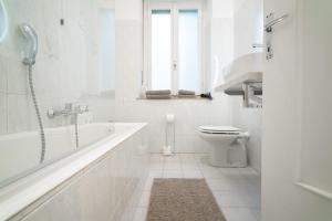 La salle de bains blanche est pourvue d'une baignoire et de toilettes. dans l'établissement Spacious Apartment - 4 Bedrooms and 3 Bathrooms, à Bergame