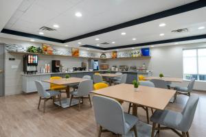 a restaurant with tables and chairs and a kitchen at Comfort Inn & Suites Hampton near Coliseum in Hampton