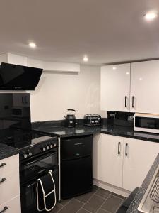 uma cozinha com electrodomésticos pretos e armários brancos em Sandy Toes : Relaxing Contemporary Victorian Apartment 10 mins to Beach em Torquay