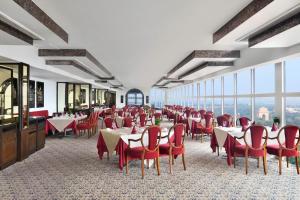 un comedor con mesas, sillas rojas y ventanas en Le Meridien New Delhi, en Nueva Delhi