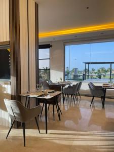 a restaurant with tables and chairs and a large window at Wissam Al-Hawra Hotel in Umm Lujj