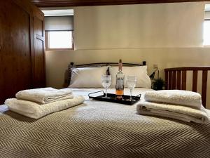 Una cama con una botella de vino y dos copas. en Maisonette Nineta, en Heraclión