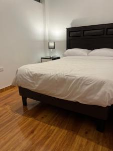 een slaapkamer met een bed en een lamp op een tafel bij Apartamento familiar a 10 min auto de Plaza Armas Lima in Lima