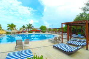 een groot zwembad met ligstoelen en een prieel bij Apartasuites Samaria - Club de Playa in Santa Marta
