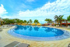 een groot zwembad met stoelen en parasols op een resort bij Apartasuites Samaria - Club de Playa in Santa Marta
