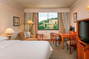 um quarto de hotel com uma cama, uma secretária e uma televisão em Sheraton Pretoria Hotel em Pretoria