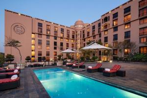 un hôtel avec une piscine, des chaises et un bâtiment dans l'établissement Sheraton Pretoria Hotel, à Pretoria