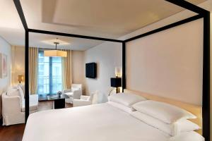 a bedroom with a white bed and white chairs at Le Metropolitan, Paris Tour Eiffel, a Tribute Portfolio Hotel in Paris