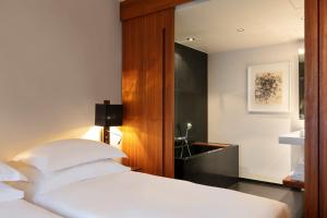 a bedroom with a white bed with a wooden headboard at Le Metropolitan, Paris Tour Eiffel, a Tribute Portfolio Hotel in Paris