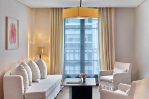 a living room with white furniture and a large window at Le Metropolitan, Paris Tour Eiffel, a Tribute Portfolio Hotel in Paris