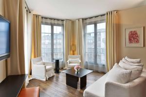 a living room with a couch and chairs and a tv at Le Metropolitan Paris Tour Eiffel, a Tribute Portfolio Hotel in Paris