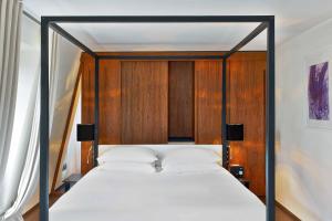 a bedroom with a bed with a wooden headboard at Le Metropolitan, Paris Tour Eiffel, a Tribute Portfolio Hotel in Paris