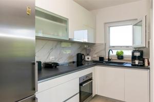 a kitchen with white cabinets and a sink and a window at Apartment Sweet Dream Manjiga in Nečujam