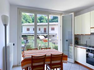 eine Küche mit einem Tisch mit Stühlen und einem großen Fenster in der Unterkunft La Spiaggia Apartment in Bellagio