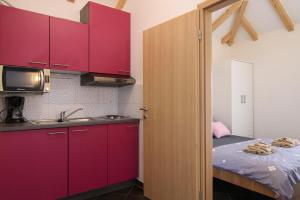 cocina con armarios rojos, fregadero y cama en Apartments Trabakul, en Trogir