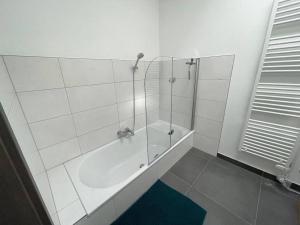 a white bathroom with a shower and a tub at ZeiTraum Oberwiehl - Wohnen im Penthouse in Wiehl