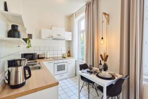 a kitchen with white cabinets and a table with chairs at STUDIO3 zentral und ruhig mit Parkplatz, 5 min z Bali-T und GOP, Boxspringbett in Bad Oeynhausen