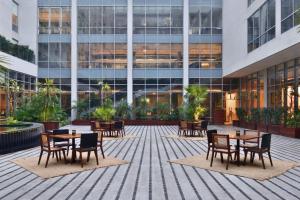 a courtyard with tables and chairs in front of a building at Aloft New Delhi Aerocity in New Delhi