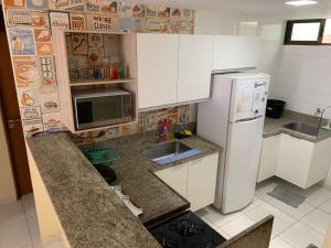 La cuisine est équipée de placards blancs et d'un réfrigérateur blanc. dans l'établissement Atlantis Aquamarine, à João Pessoa