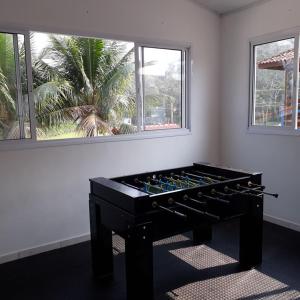 a black foosball table in a room with two windows at Recanto Vizinho do Mar in Ubatuba