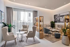 Residence Inn by Marriott Sheikh Zayed Road, Dubai في دبي: غرفة انتظار مع كراسي وطاولات ونافذة
