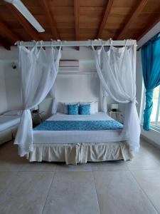 a bedroom with a bed with white curtains at hotel 3 banderas Manzanillo del Mar in Cartagena de Indias