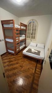 a room with two bunk beds and a wooden floor at Nuh Hostel - Lourdes in Belo Horizonte