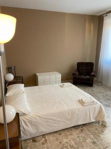 een slaapkamer met een wit bed en een stoel bij Casa Anna in Ravenna