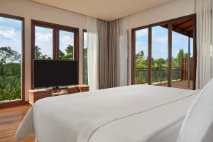a bedroom with a large bed and a television at Element Bali Ubud in Ubud