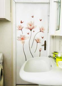 baño con lavabo blanco con flores rosas en la pared en La Casa dei Panorami, en Castelsaraceno