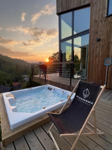 a hot tub on the deck of a house with a chair at Widokownia Brenna in Brenna