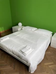 - une chambre avec un lit blanc et un mur vert dans l'établissement Casa Anna, à Ravenne