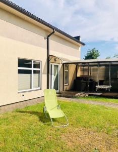 a green chair sitting in the grass in front of a house at Baltic retreat house in Ventspils