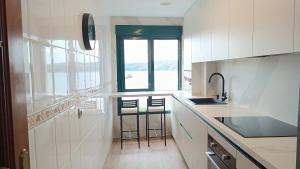 a kitchen with a counter and two stools in it at SALSEIRAZO - PLAYA A RIBEIRA MIÑO in Miño