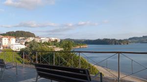 zwei Bänke auf einem Balkon mit Blick auf einen Wasserkörper in der Unterkunft SALSEIRAZO - PLAYA A RIBEIRA MIÑO in Miño