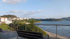 two benches sitting on a balcony overlooking a body of water at SALSEIRAZO - PLAYA A RIBEIRA MIÑO in Miño