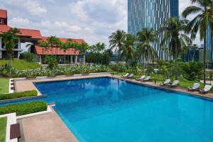 a large swimming pool with chairs and a building at Palm Garden Hotel, Putrajaya, a Tribute Portfolio Hotel in Putrajaya