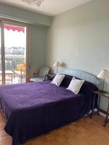 ニースにあるConstellations de Fabronの紫色のベッドとバルコニー付きのベッドルーム1室
