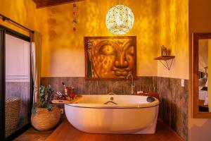 a bath tub in a bathroom with a face on the wall at Shiva Boutique Hotel - Praia do Rosa in Praia do Rosa