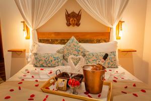 uma cama com uma bandeja cheia de corações vermelhos em Shiva Boutique Hotel - Praia do Rosa em Praia do Rosa