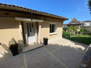 een klein huis met een veranda met twee potplanten bij T2 Neuf, parking & garage privé, proche centre in Sarlat-la-Canéda